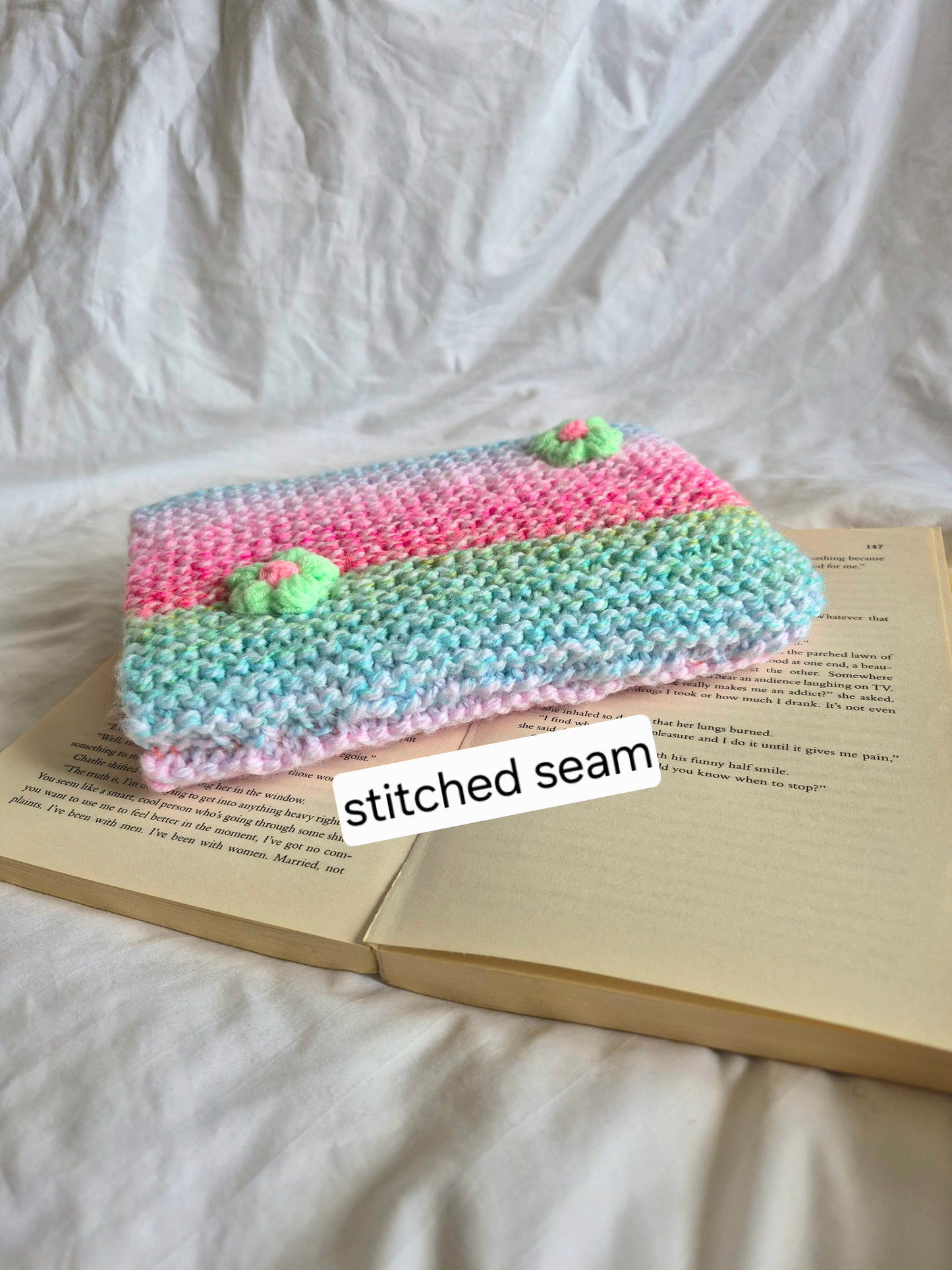 Rainbow knitted book sleeve with green flowers