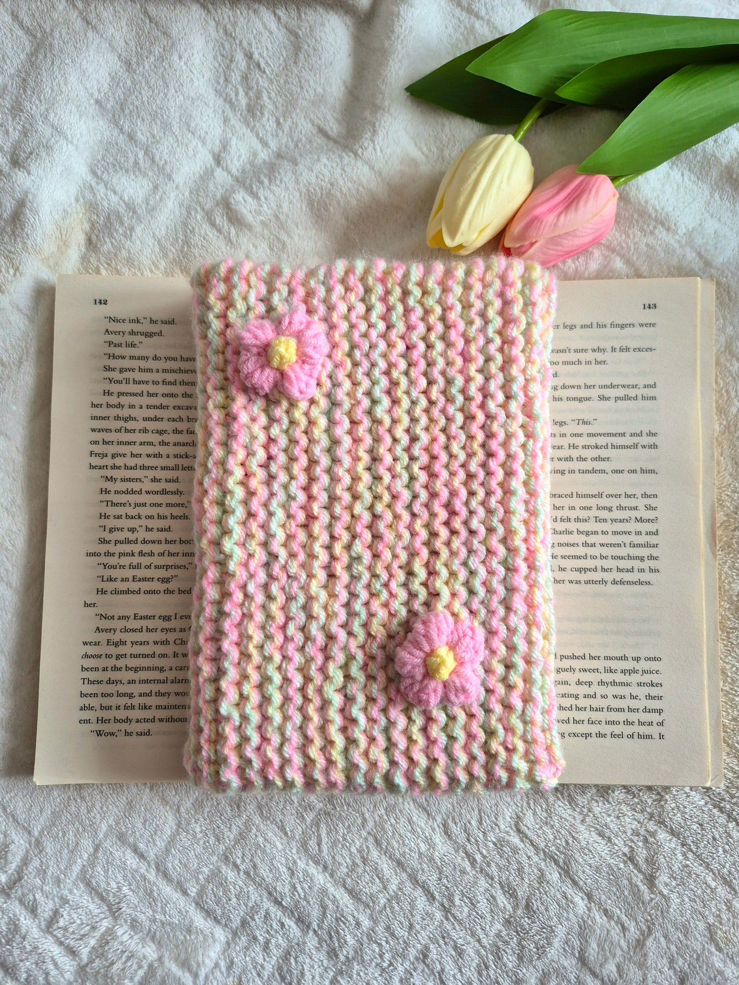 Multicoloured knitted book sleeve: Green, pink and yellow with pink flowers