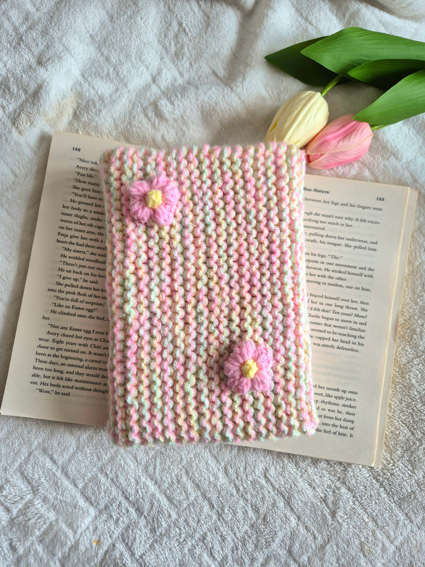 Multicoloured knitted book sleeve: Green, pink and yellow with pink flowers