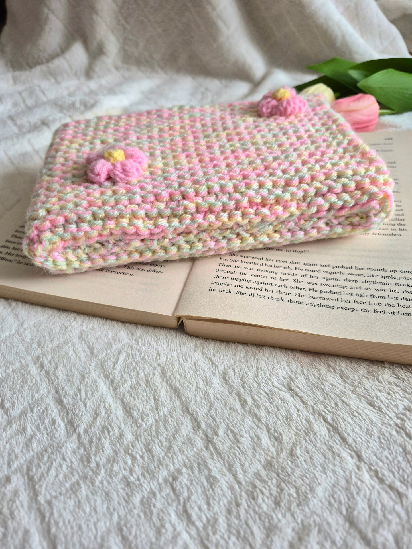 Multicoloured knitted book sleeve: Green, pink and yellow with pink flowers